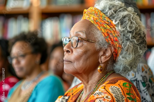 Elegant Senior African American Woman with Stylish Glasses and Headscarf in a Thoughtful Pose at Social Gathering