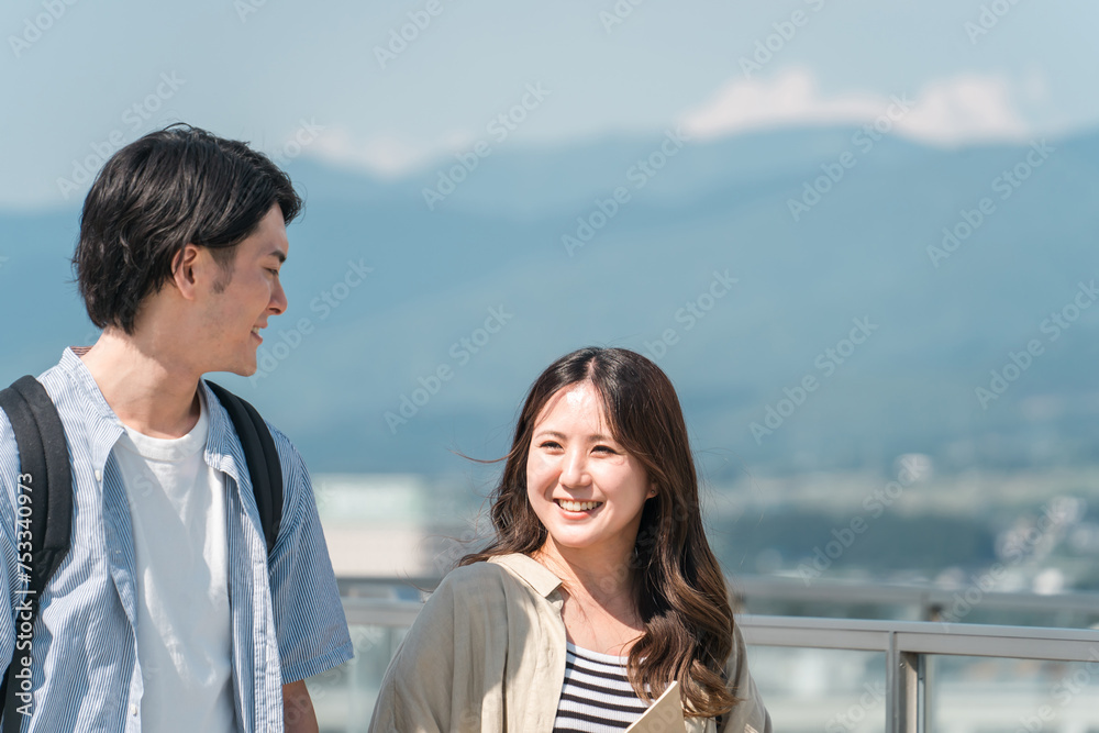 屋外を歩くカップル（大学生・学生・キャンパスライフ・仲良し）
