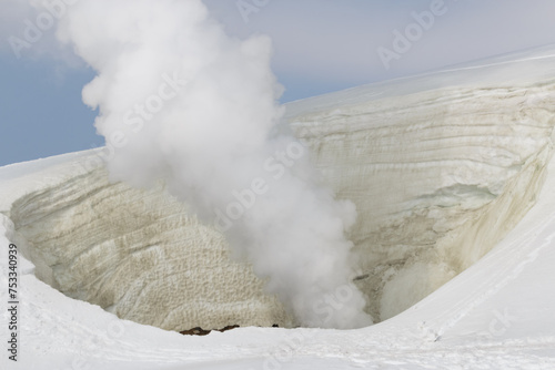 Close up of steam rising from volcano fumarole in winter snow photo