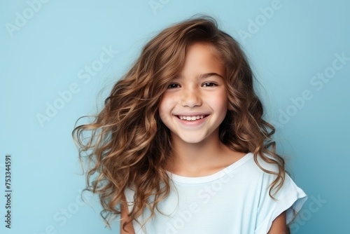 Portrait of a cute smiling little girl with long curly hair over blue background