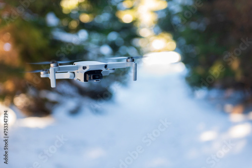A grey drone flying in the forest.