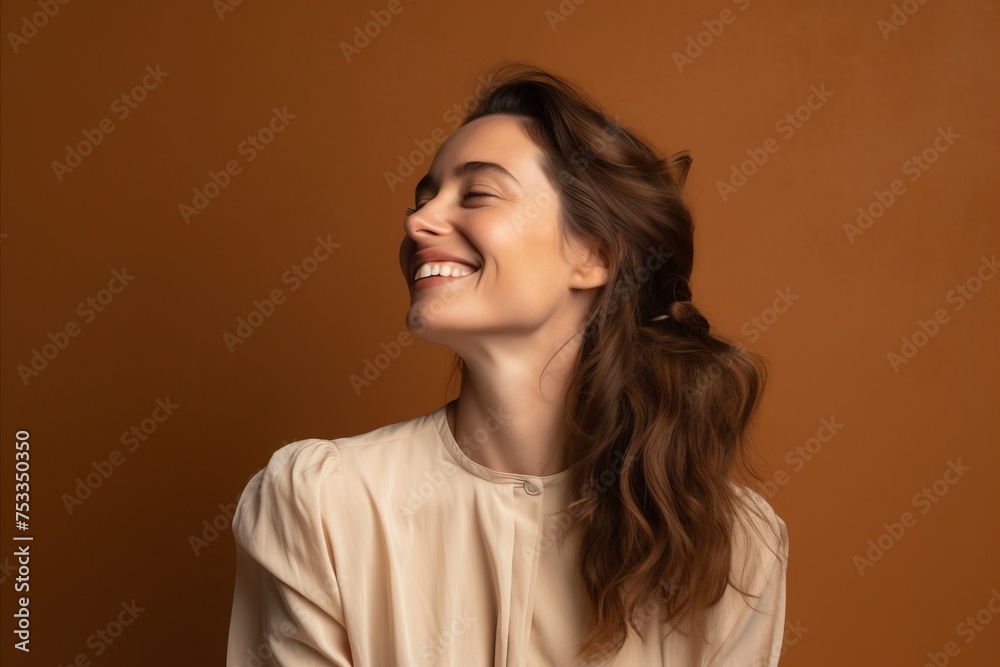 Beautiful young woman with closed eyes laughing and looking up on brown background Beautiful young woman with closed eyes laughing and looking up on brown background