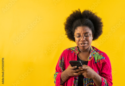 retrato de estudio de joven afroamericana escribiendo por celular mensaje de texto  photo