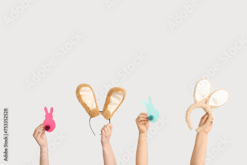 Female hands holding Easter bunny ears headbands and paper rabbits on white background