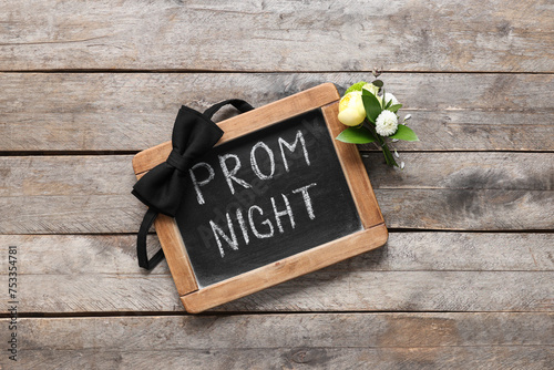 Chalkboard with text PROM NIGHT, bow tie and boutonniere on wooden background