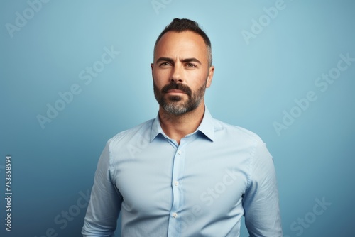 Portrait of a handsome bearded mature man in shirt on blue background. © Loli