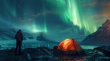A man camping in the mountains gazes at the breathtaking green Northern Lights.