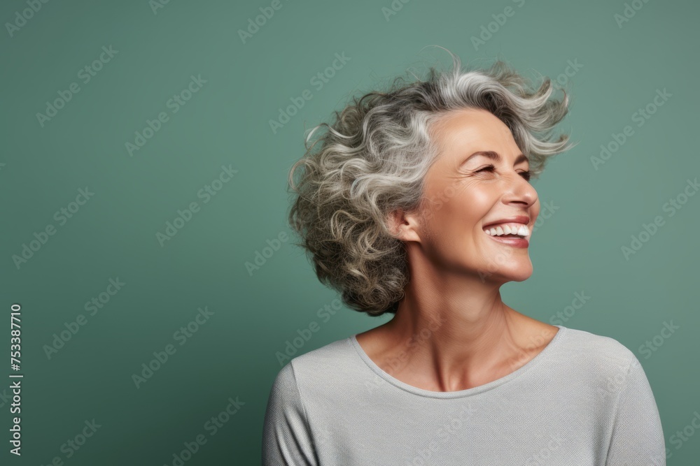Portrait of smiling middle aged woman with grey hair on green background Portrait of smiling middle aged woman with grey hair on green background