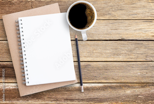 Top view of notebook pencil and cup of coffee on wood table background.