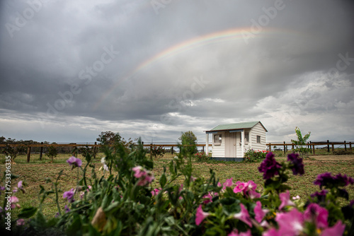 Grey sky and Small rainbow above a tiny white house 