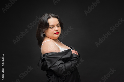 A woman in a black jacket wears a white bra. The concept of confidence and empowerment as a woman proudly shows off her bra. A black jacket adds sophistication. Fat woman.