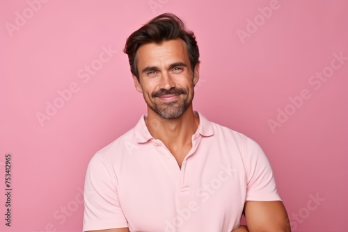 Portrait of handsome man in casual clothes looking at camera and smiling while standing against pink background © Stocknterias