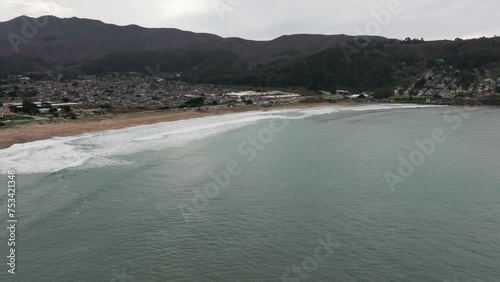 slow dramatic drone shot panning to the left of surfers in the ocean photo