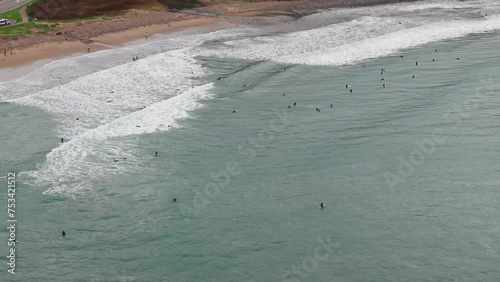 Drone shot flying over surfers in the pacific ocean with large waves photo