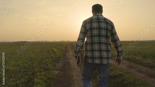 A farmer in a motley shirt walks across a cultivated field in the evening. © Марія Шурубура