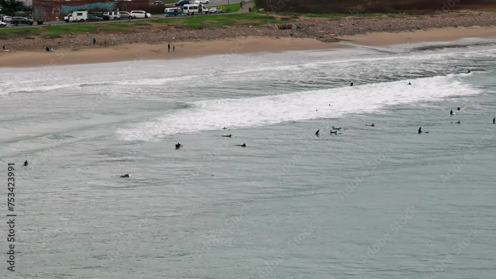 Drone shot panning across the beachfront with waves crashing and surfers waiting Drone shot panning across the beachfront with waves crashing and surfers waiting