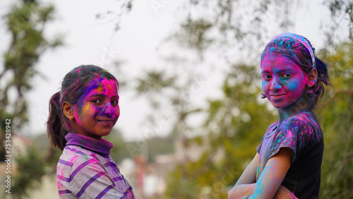 Indian cute happy child celebrate Indian holi festival with colorful paint powder on faces and body