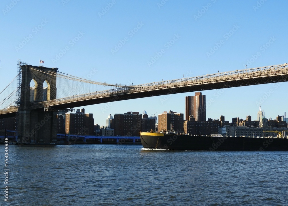 Naklejka premium boat passing the brooklyn bridge