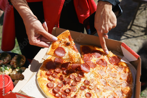 A person is holding a slice pepperoni pizza