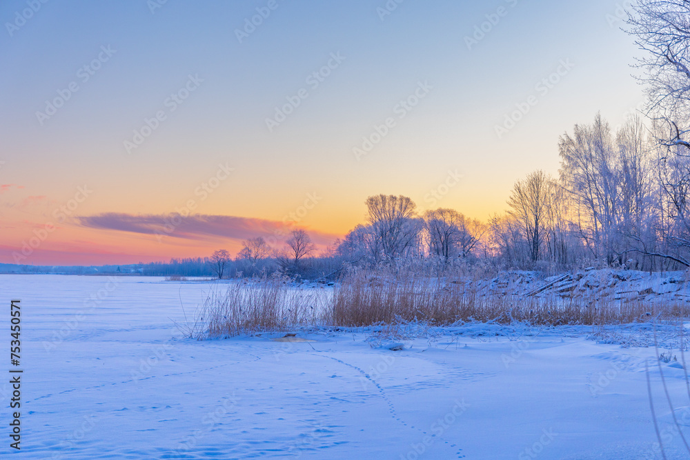 A beautiful winter sunrise scenery of frozen lake and forest. Colorful landscape with dawn skies in Northern Europe. A beautiful winter sunrise scenery of frozen lake and forest. Colorful landscape with dawn skies in Northern Europe.