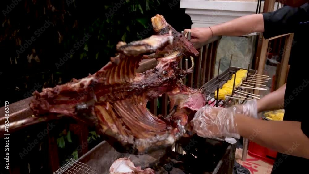 Chef's is cutting goat meat using knife from grilled roasted goat . Chef's is cutting goat meat using knife from grilled roasted goat .