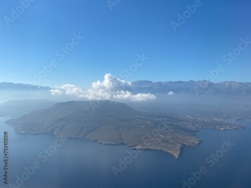 top view of an island in the sea with clouds and mountains on a sunny day
