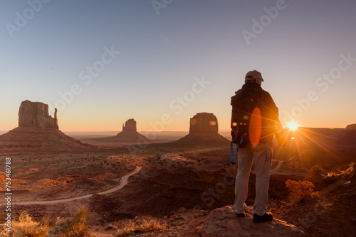 A tourist watching sunrise at Monument Valley. silhouette of a person on the top of the rock