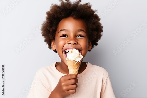Dark-skinned African child eating ice cream in a cone and smiling happily on a pink background © photolas