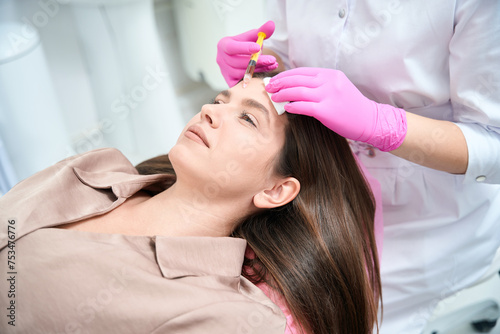 Medical worker on cosmetology procedure with woman