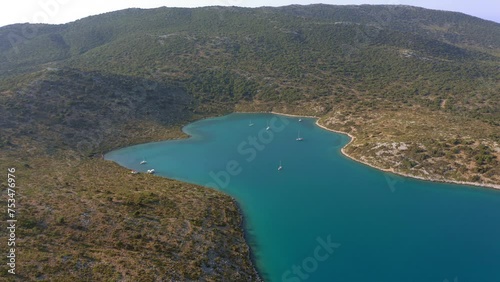 Aerial: Slow panning drone shot of planitis bay of the island of Kira Panagia in Sporades, Greece with amazing turquoise and emerald crystal clear water photo