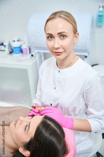 Professional beautician on cosmetology procedure for skin with female