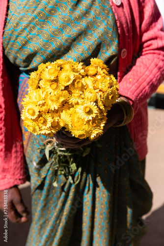 Woman holding in hands marigold flower and reating a mandala with flower petals. Religion and yoga concept. photo