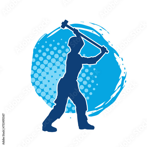 Silhouette of a worker in action pose using his sledge hammer tool.