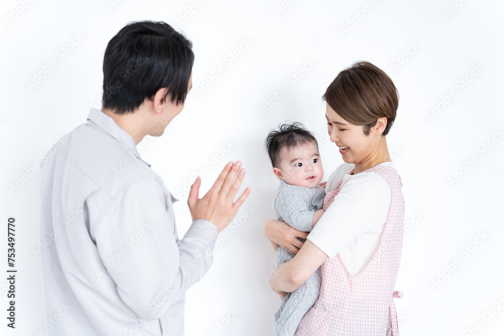 手を振る作業着を着た男性と子供を抱く女性