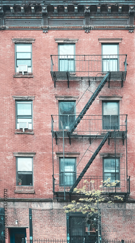 Old red brick building with fire escapes, color toning applied, New York City, USA.