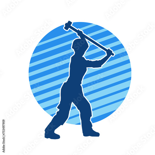 Silhouette of a worker in action pose using his sledge hammer tool.