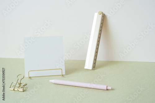 Blank memopad with gold metallic holder, ruler, pen, clip on desk. white ivory background. workspace office stationery photo