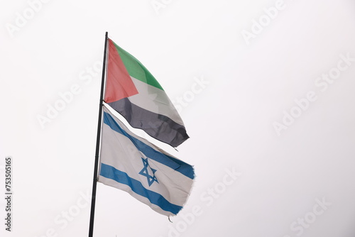 A flag with a white star and blue stripes is flying next to another flag