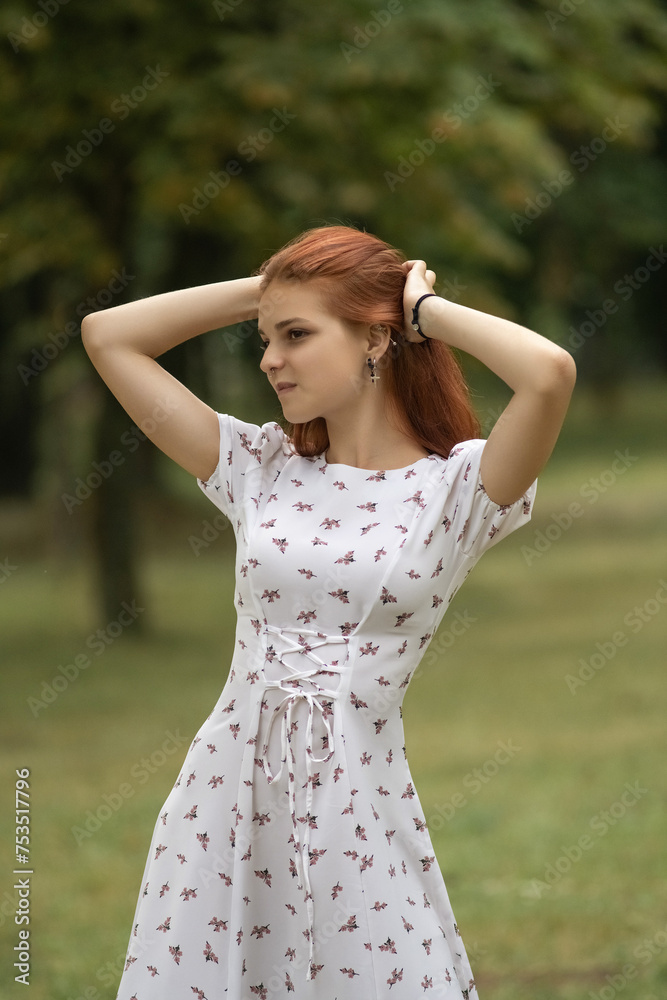 Portrait of a young beautiful red-haired girl in a dress in a summer park. Portrait of a young beautiful red-haired girl in a dress in a summer park.
