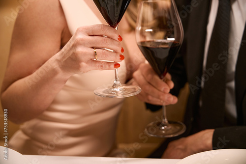 Couple in evening dresses with glasses of red wine