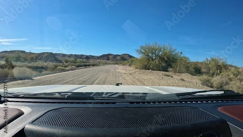 POV - Driving on gravel road along the main Gila Gravity Canal for irrigation near Yuma AZ; disperse camping along the road; dash and hood of the vehicle are visible