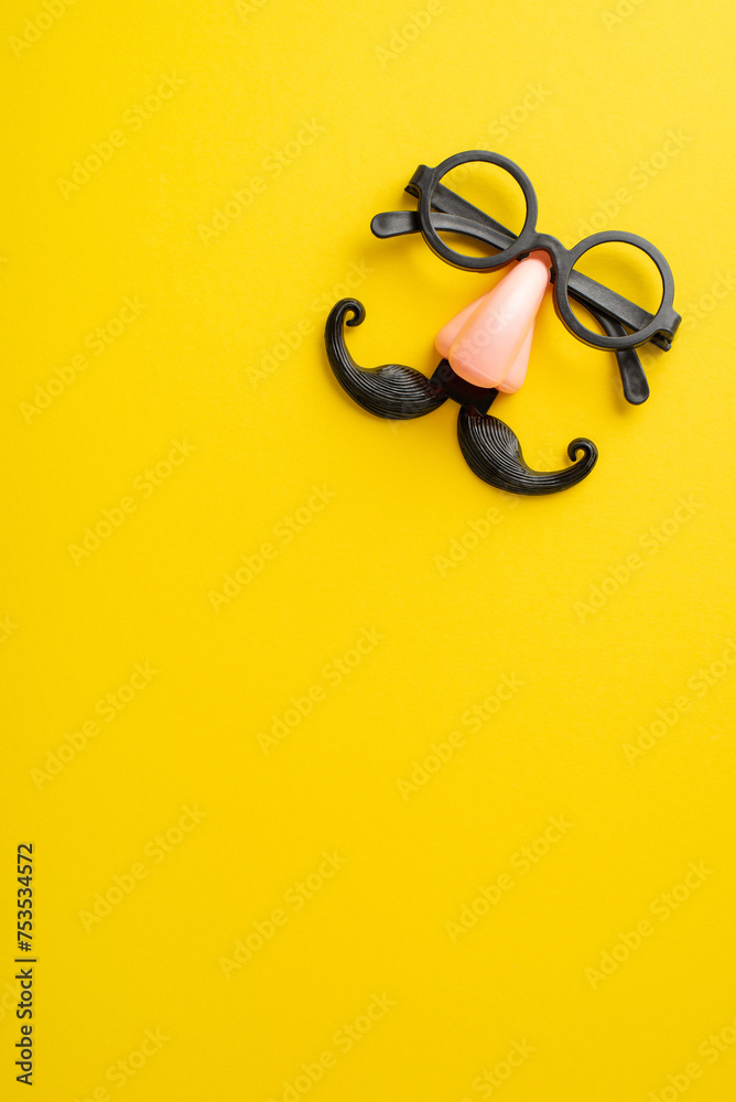 Get into the April Fool's spirit: Vertical top view of comical eyewear with a faux mustache and nose, showcased on a bright yellow canvas, with space for your personalized text or ad - obrazy, fototapety, plakaty 