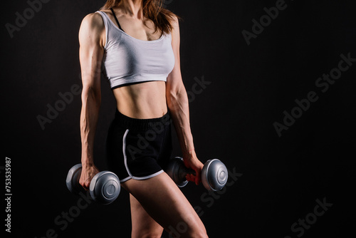 Sporty female doing exercise with dumbbells, silhouette studio shot dark yellow background