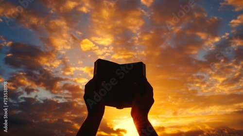 Silhouette of hands holding a Bible towards the sky