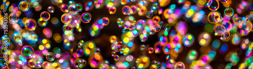 Colorful soap bubbles against a dark background. Colorful iridescent covers float together with ephemeral elegance. Reflections and transparent surfaces with spatial depth with selective focus.
