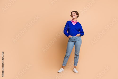 Full size photo of attractive young woman posing look empty space promo dressed stylish blue clothes isolated on beige color background