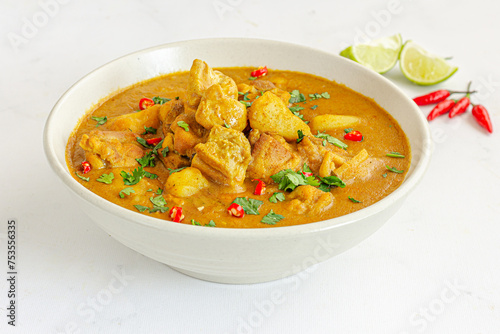 Thai Chicken Curry in a Bowl with Cilantro and Lemon on White Background Close Up Photo
