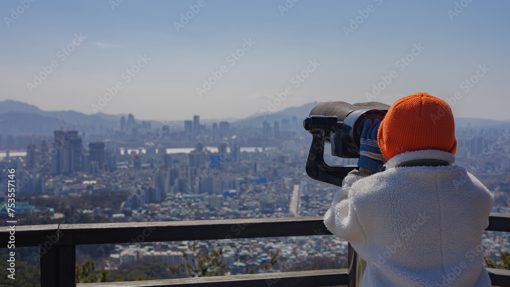 A child looking at the scenery of Seoul through binoculars at the observation deck of mountain Achasan.