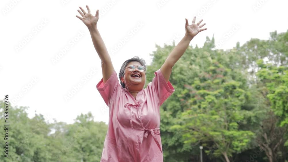 An elderly Asian female patient is in the garden outside. She raised her arms and smiled cheerfully and happily. Senior health care. medical services An elderly Asian female patient is in the garden outside. She raised her arms and smiled cheerfully and happily. Senior health care. medical services
