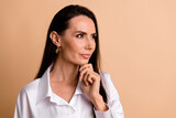Photo of pretty intelligent manager lady hand touch chin look interested empty space isolated on beige color background